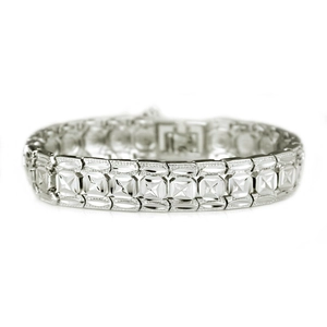 Macro detail of silver watch-style bracelet featuring geometric square links and textured patterns