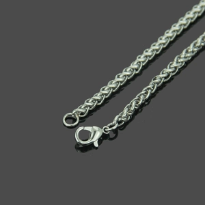 Détail de la chaîne argentée à maille épi montrant la texture tressée et le fermoir mousqueton