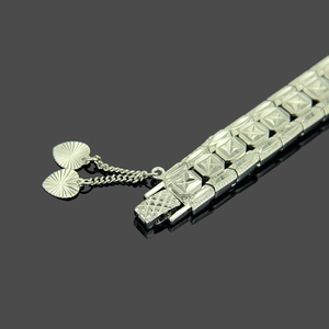 Detail of silver watch-style bracelet with star patterns and heart-shaped charms