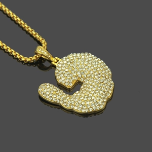 Détail macro du pendentif crevette doré avec cristaux pavés sur une chaîne boîte ronde