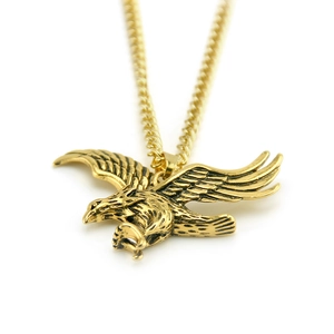 Gros plan détaillé du pendentif aigle doré avec plumes texturées et chaîne gourmette