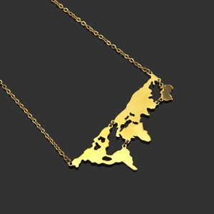 Gold stainless steel world map pendant necklace with fine chain on reflective background