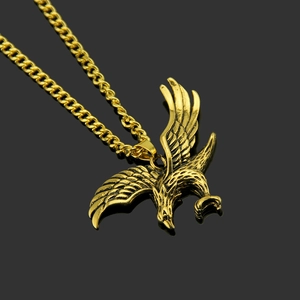Collier hip-hop doré avec pendentif aigle aux ailes détaillées sur fond noir profond