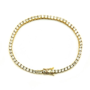 Macro detail of gold tennis bracelet featuring four-prong set sparkling cubic zirconia stones