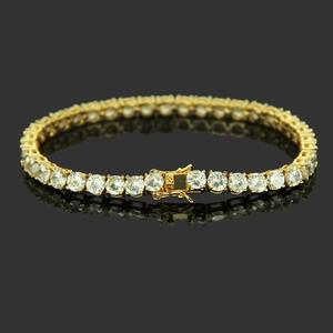 Iced out gold copper tennis bracelet with sparkling cubic zirconia on a black reflective surface
