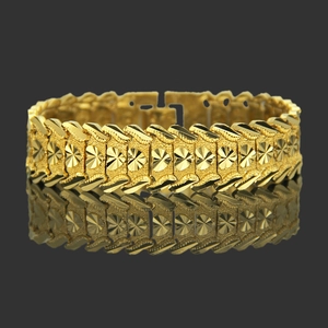 Chunky gold hip hop bracelet with heart pattern and serrated edges on dark background