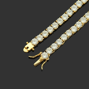 Golden tennis bracelet with clear cubic zirconia on a black reflective background