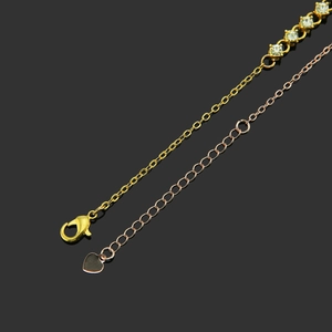 Elegant gold and rose gold rhinestone bracelet with heart tag on a sleek black background