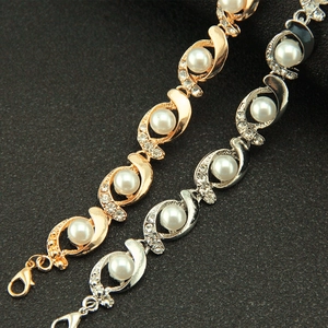 Detail of elegant gold and silver pearl bracelets with sparkling rhinestones on black