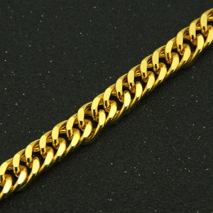 Detailed macro view of gold-plated hip hop Cuban link chain on textured black surface