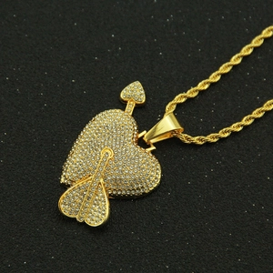 Macro shot of hip-hop iced-out heart and arrow pendant with a golden rope chain