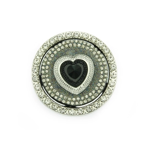 Close-up of a circular rotating jewelry accessory with black heart stone and crystals