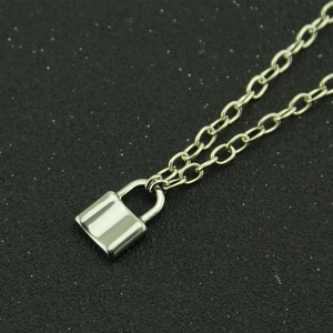 Macro view of a polished silver padlock pendant on a slim O-link chain necklace