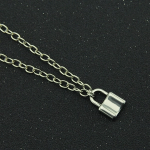 Close-up of polished silver padlock pendant on a fine link chain over black background