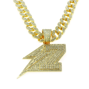 Macro detail of iced-out lightning bolt pendant with sparkling crystals on gold Cuban chain