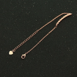 Detail of rose gold bracelet with heart charm, square zircon stones and lobster clasp