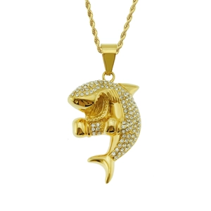 Détail macro du pendentif requin doré avec des strass blancs scintillants sur une chaîne corde