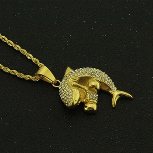 Détail du pendentif requin doré serti de strass sur une chaîne torsadée