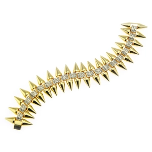 Détail d'un large bracelet punk doré avec pointes métalliques et strass blancs incrustés