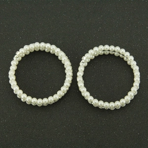 Detailed view of two triple-layered spiral bracelets with white pearls and sparkling rhinestones