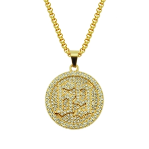 Detail of hip-hop gold plated pendant with Gothic letters and pavé set sparkling crystals