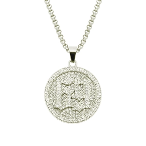 Macro shot of silver hip-hop pendant with pavé crystals and letters B and H