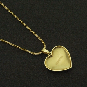 Macro shot of gold broken heart pendant with brand engraving on black matte texture