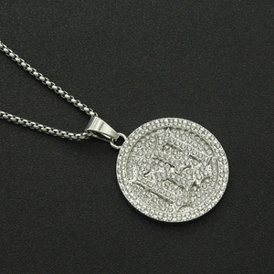 Macro detail of iced-out hip hop round medallion pendant with gothic letter on silver box chain