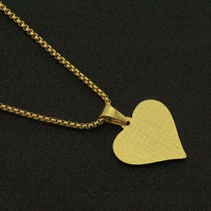 Vista detallada de un colgante de corazón dorado con reverso texturizado y cadena box