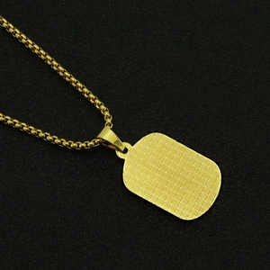 Détail macro du collier pendentif géométrique doré avec une surface quadrillée