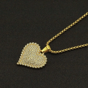 Hip hop style gold heart pendant with iced-out diamonds on a black textured background