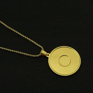 Detailed macro shot of a gold round medallion pendant necklace with brushed metal texture