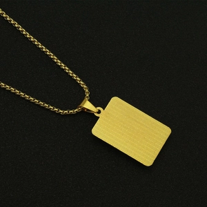 Close-up of golden rectangular dog tag pendant with grid texture on a box chain