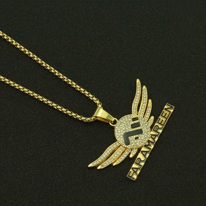 Hip hop gold angel wings pendant necklace with diamonds on black textured surface