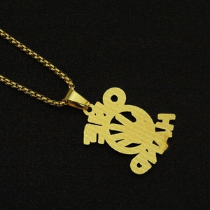 Dettaglio di un ciondolo dorato con lettere stilizzate su una catena a maglia box