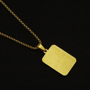 Macro detail of golden box chain and textured rectangular dog tag pendant for men