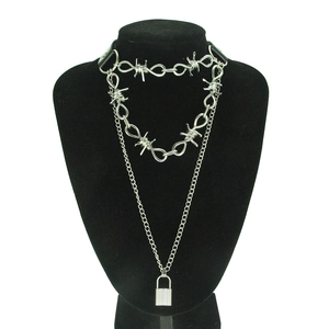 Close-up of layered punk necklaces with barbed wire choker and lock pendant