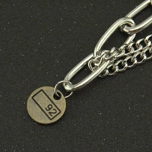 Détail d'une chaîne double épaisseur avec un pendentif rond gravé du numéro 92