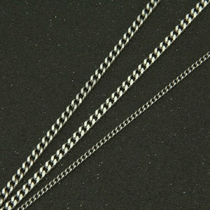 Close-up of three polished stainless steel Cuban link chains in different widths