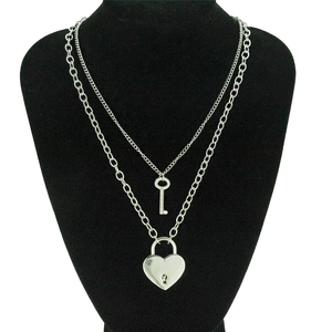 Détail d'un collier double épaisseur en argent avec pendentifs cœur et clé sur buste noir