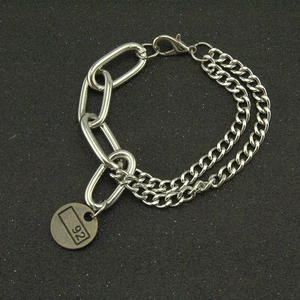 Silver Cuban link bracelet with vintage round charm and lobster clasp on dark background