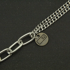 Minimalist Cuban link chain bracelet with a vintage round numeric pendant and sleek metal finish