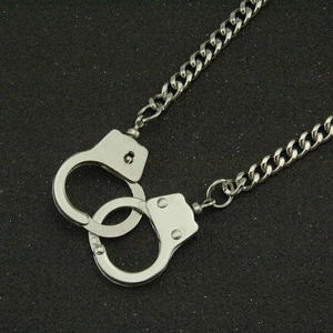 Punk style silver handcuff pendant necklace with cuban chain over black glitter