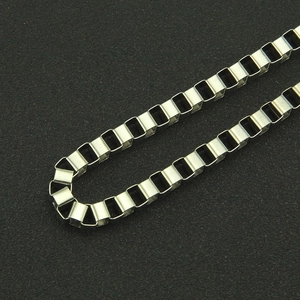 Close-up of hip hop silver box chain texture with hollow cube links on black background