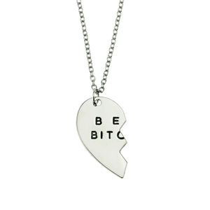 Close-up of silver-tone split heart pendant with engraved lettering on a metal chain