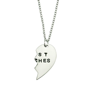 Detail of silver heart-shaped pendant with ST CHES engraving on a delicate link chain
