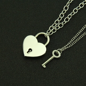 Ensemble collier avec pendentif cadenas cœur et clé argentée sur fond noir mat