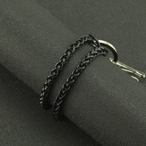 Punk black woven chain belt with silver lobster clasp on textured grey background