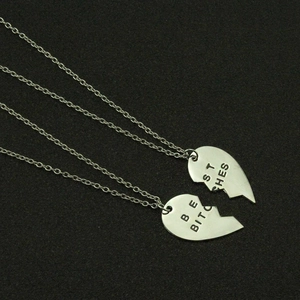 Matching silver split heart necklaces with Best Bitches engraving on black background