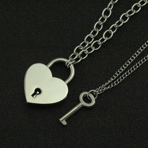 Ensemble collier avec pendentif cadenas cœur poli et clé sur fond noir texturé